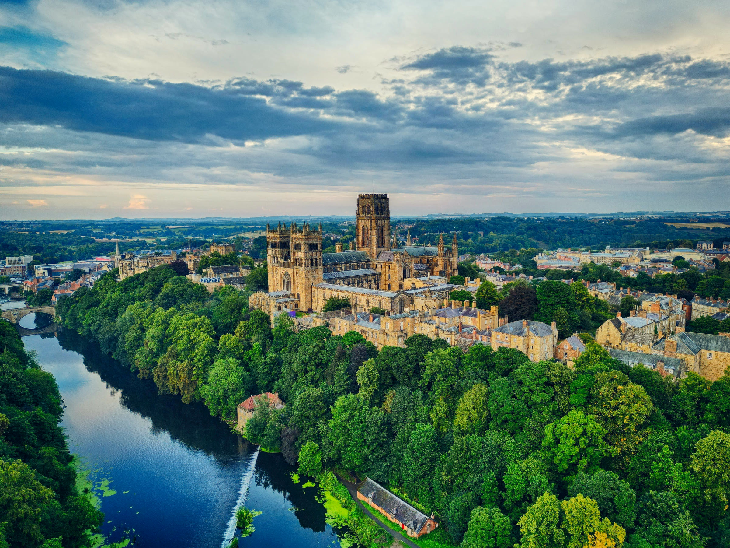 Aerial view of Durham Cathedral and its towers above the wooded banks of the River Wear